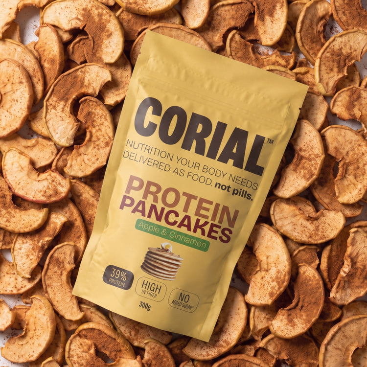 
                    
                      Embalagem CORIAL Protein Pancakes Maçã e Canela sobre fatias de maçã desidratada com canela
                    
                  