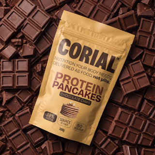 Embalagem CORIAL Protein Pancakes Pepitas de Chocolate sobre pedaços de tablete de chocolate negro