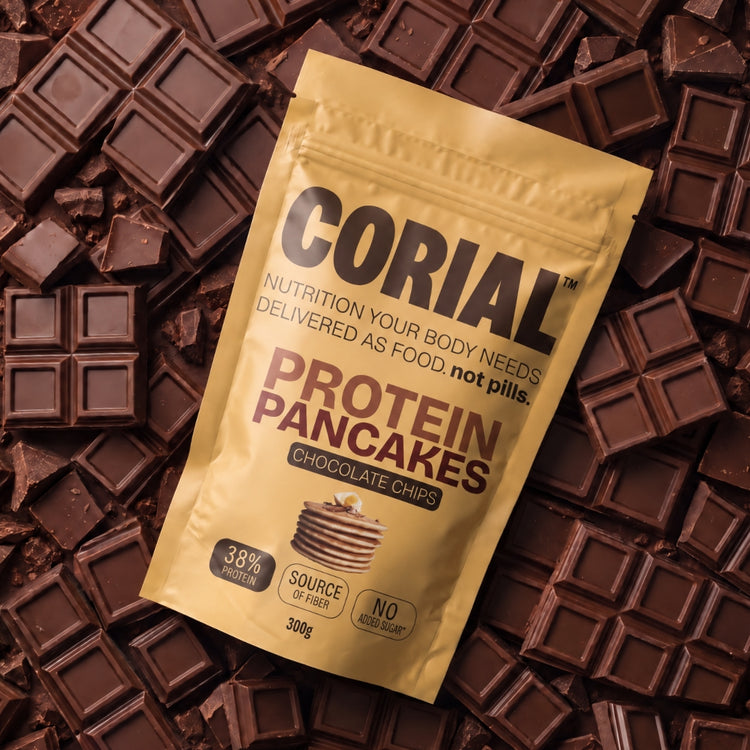 Embalagem CORIAL Protein Pancakes Pepitas de Chocolate sobre pedaços de tablete de chocolate negro